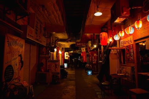 装饰灯笼照亮的商店之间的黑暗狭窄的街道 · 免费素材图片