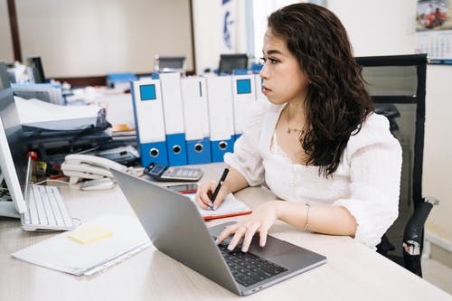 使用macbook Pro的白色长袖衬衫的女人 · 免费素材图片