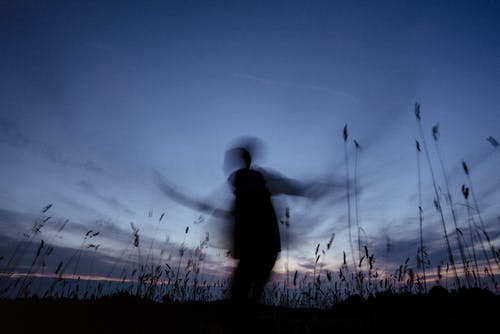 夜间站在草地上的人的身影 · 免费素材图片