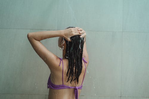 比基尼在宽敞的浴室洗头的苗条女人 · 免费素材图片