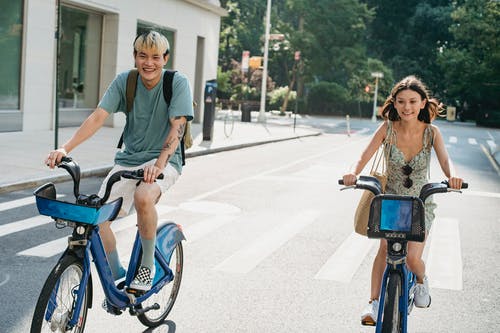 正面夫妇在城市的街道上骑自行车 · 免费素材图片