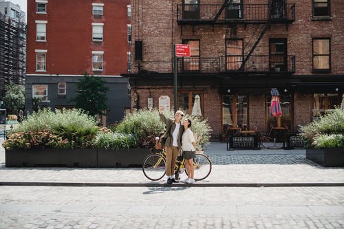性格开朗时尚的年轻夫妇，在城市街道上的老建筑附近采取自拍照 · 免费素材图片