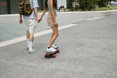 滑板时用手拿着男友的匿名女人滑板 · 免费素材图片