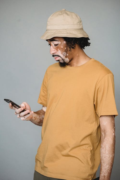 使用智能手机聚焦皮肤色素沉着的黑人男性 · 免费素材图片