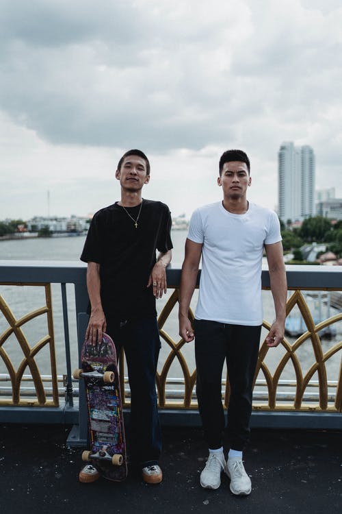 亚洲年轻男子与滑板在河大堤上 · 免费素材图片