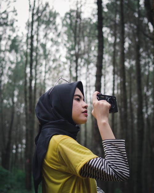 黑色和白色的条纹的长袖衬衫，拿着黑色相机的女人 · 免费素材图片
