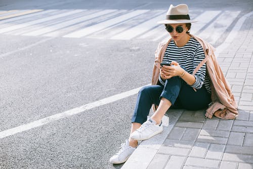 黑色和白色的条纹的衬衫和蓝色牛仔牛仔裤，坐在灰色的混凝土路上的女人 · 免费素材图片