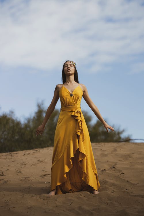 黄色的裙子站在棕色的沙滩上的女人 · 免费素材图片