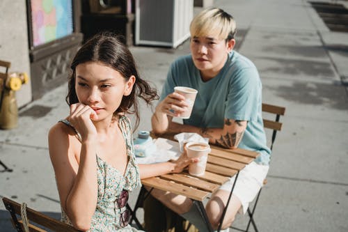 多种族的夫妇，在大街上的餐桌上的外卖咖啡 · 免费素材图片