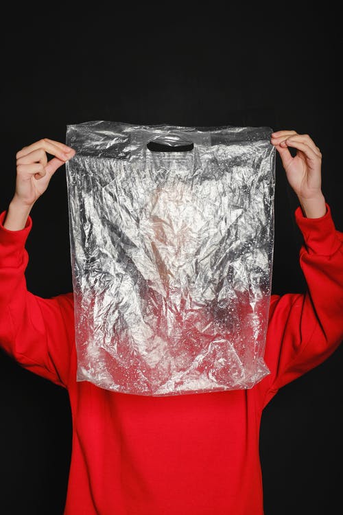 穿着红顶的人拿着透明的塑料袋 · 免费素材图片