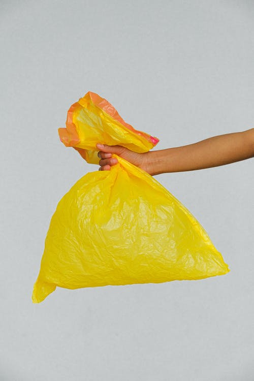 手里拿着黄色的塑料袋 · 免费素材图片