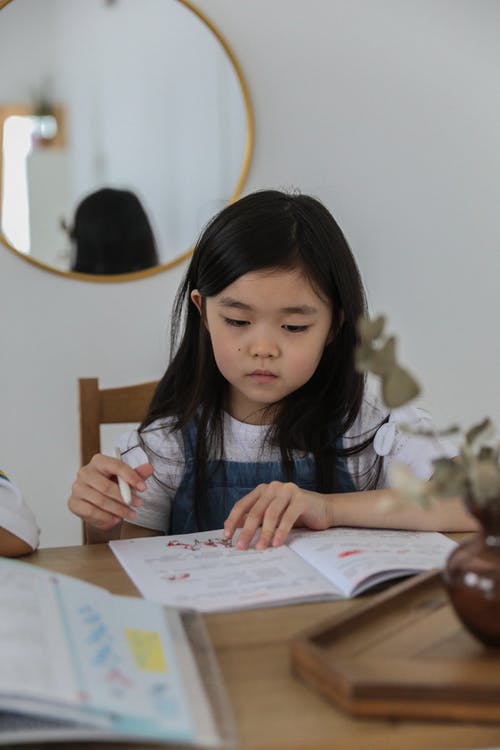 做作业的体贴的亚裔女孩 · 免费素材图片