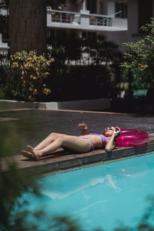 放松在热带度假胜地池畔上的寒意女人 · 免费素材图片