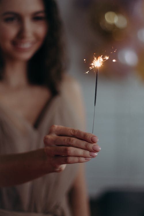 女人拿着火花的浅焦点照片 · 免费素材图片