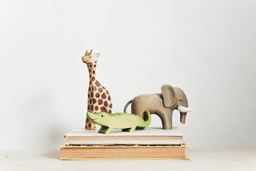 书上的棕色和绿色长颈鹿雕像 · 免费素材图片
