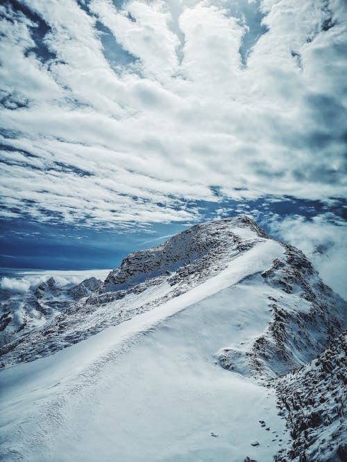 多云的天空下的积雪的山 · 免费素材图片