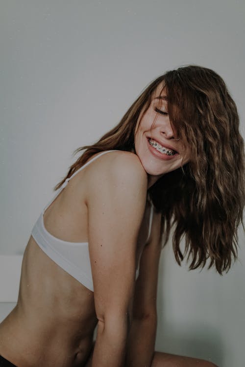 胸罩的快乐的妇女微笑和展示牙固定器的 · 免费素材图片