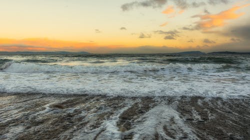 海浪在日落时在岸上崩溃 · 免费素材图片