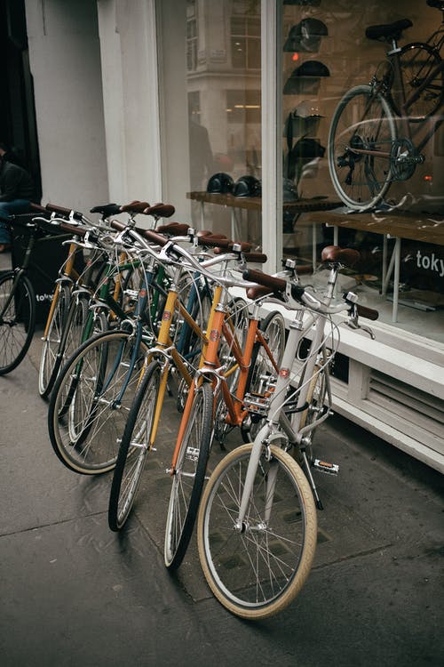 白色和棕色的城市自行车停在玻璃窗旁边 · 免费素材图片