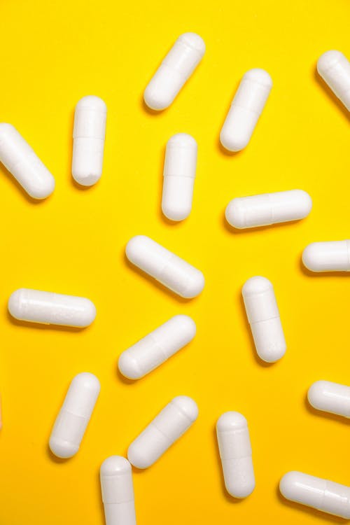 黄色表面上的白色药物胶囊 · 免费素材图片