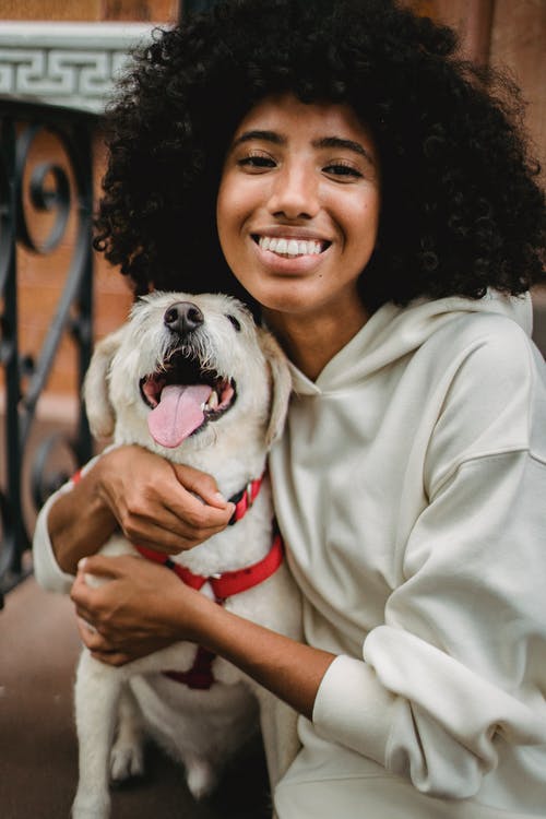 幸福的黑女人拥抱狗在大街上 · 免费素材图片