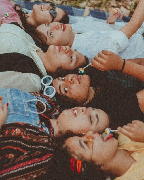 一群女人躺在毯子上吃棒棒糖 · 免费素材图片