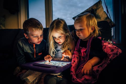 三个孩子看着一台平板电脑 · 免费素材图片