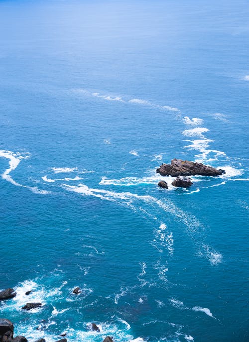 浅蓝色的海水洗粗糙的岩石 · 免费素材图片