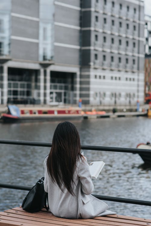 享受与书的消遣在堤防上的年轻女子 · 免费素材图片