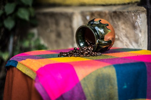 棕色和黑色陶瓷咖啡豆架，粉红色绿色和黄色纺织 · 免费素材图片