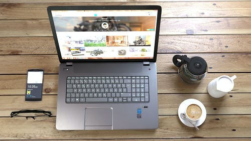 银笔记本电脑旁边咖啡杯咖啡杯和智能手机 · 免费素材图片