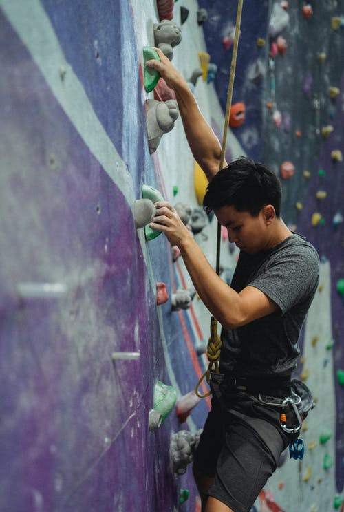 练习在攀岩墙上的亚洲运动员 · 免费素材图片