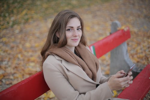坐在红色长凳上的灰色外套的女人 · 免费素材图片