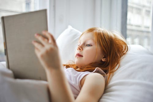 一个女孩躺在床上看书 · 免费素材图片