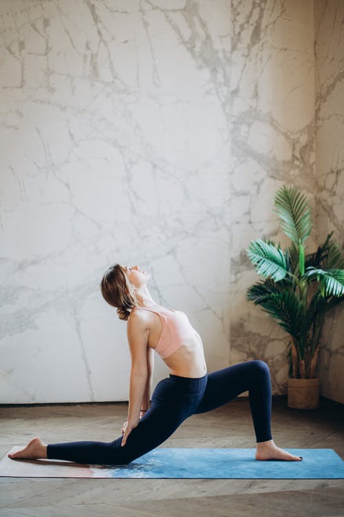 白色背心和蓝色紧身裤，在瑜伽垫上做瑜伽的女人 · 免费素材图片