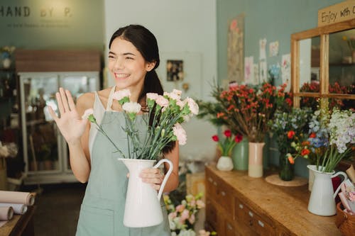 女人在店里拿着花瓶与花 · 免费素材图片