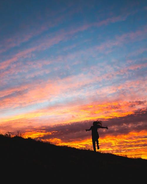 人在日落时站在山上的剪影照片 · 免费素材图片