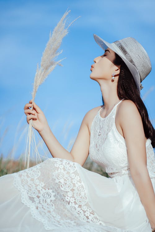 白色花卉意大利面条皮带穿着白色太阳帽的女人 · 免费素材图片