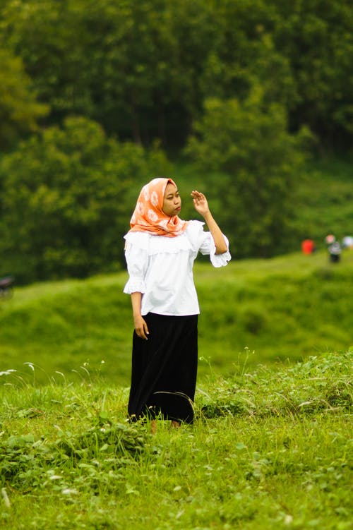 白色的长袖和黑色的裤子，站在草地上的女人 · 免费素材图片