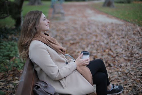 坐在长凳上的米色外套的女人 · 免费素材图片