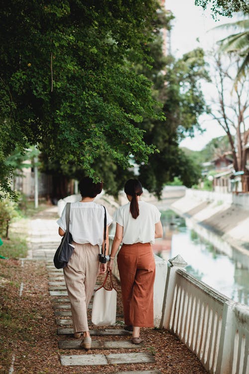 在小镇的路堤上行走的匿名妇女 · 免费素材图片