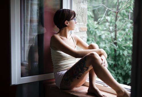 白色背心坐在窗玻璃上的女人 · 免费素材图片