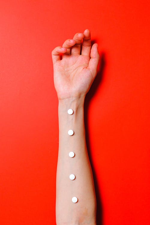 白色药片在人的手臂上的照片 · 免费素材图片