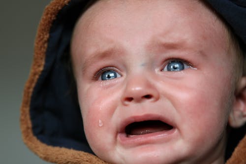 哭泣的婴儿，穿着棕色和黑色连帽上衣 · 免费素材图片