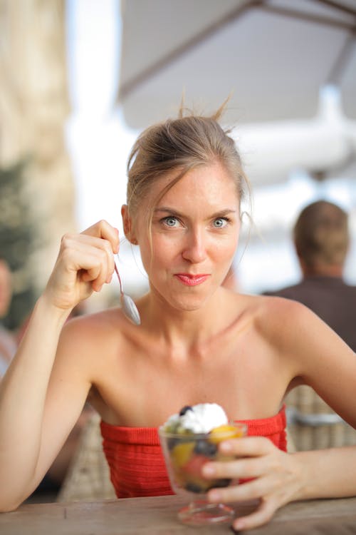 红色管顶部吃甜点的微笑女人的选择性焦点照片 · 免费素材图片
