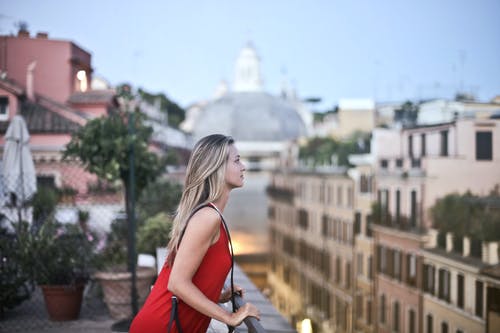 红色无袖连衣裙站在屋顶上的女人 · 免费素材图片