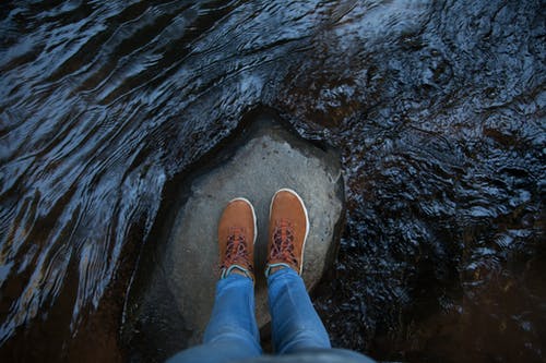 站在流水之间的岩石上的人 · 免费素材图片