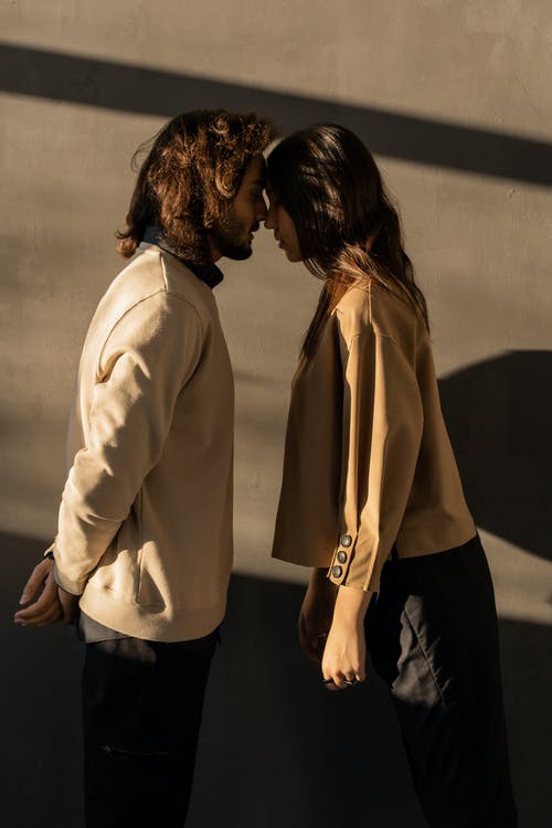 米色运动衫的男人亲吻米色西装外套和黑色裤子的女人 · 免费素材图片