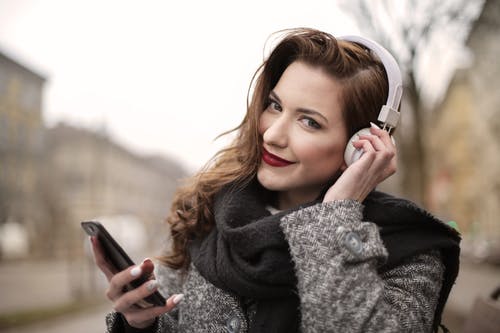 一个女人在白色耳机上听音乐的照片 · 免费素材图片