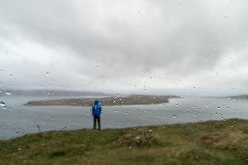 男子站在水附近的草地上 · 免费素材图片